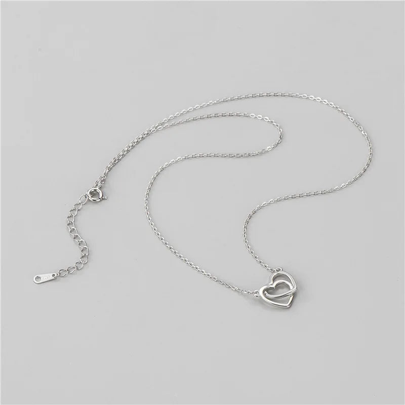 Zoom sur le pendentif double coeur ajouré du collier Lampung en argent. O-dace.com